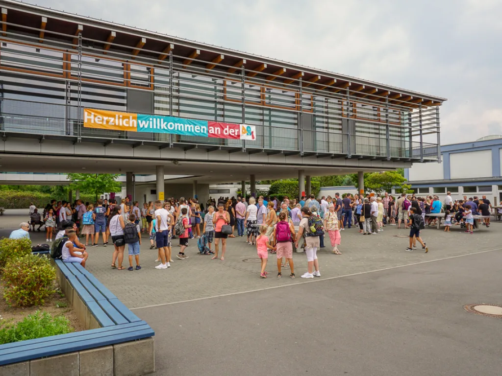 Blick über den Schulhof auf das Gebäude mit Willkommensbanner.